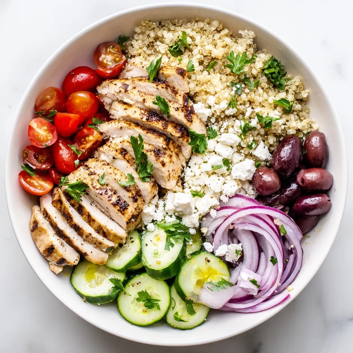 Mediterranean Chicken Quinoa Bowl topped with grilled chicken, fresh vegetables, and crumbled feta cheese
