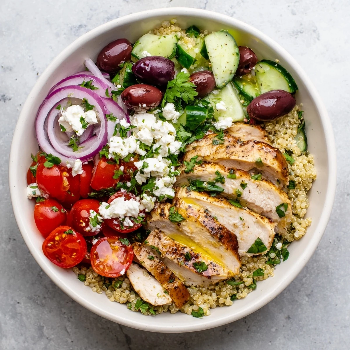 Colorful Mediterranean Chicken Quinoa Bowl with juicy sliced chicken, cucumber, tomatoes, and tangy olives