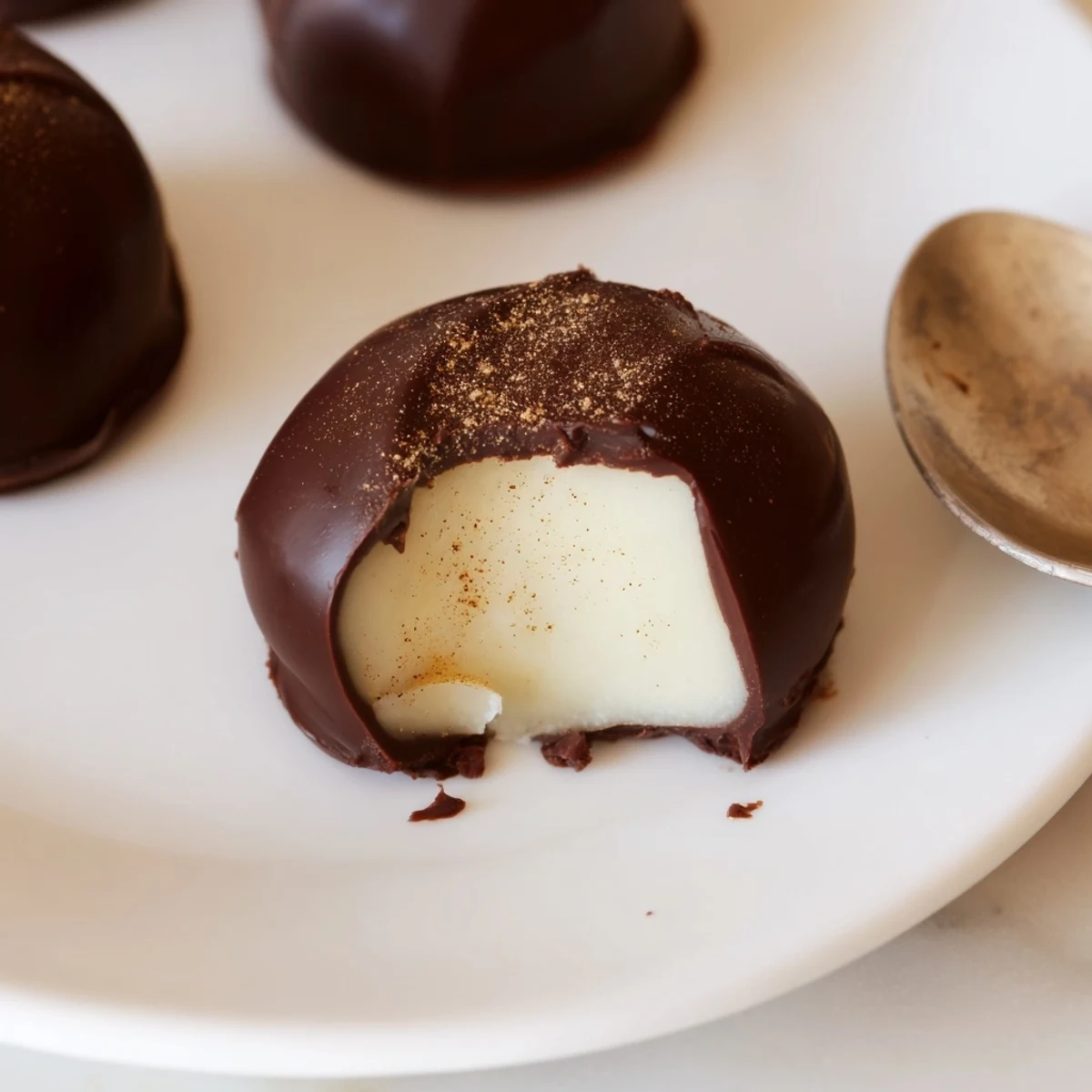Hand rolled Dark Chocolate Eggnog Truffles on a tray, creamy centers peeking.