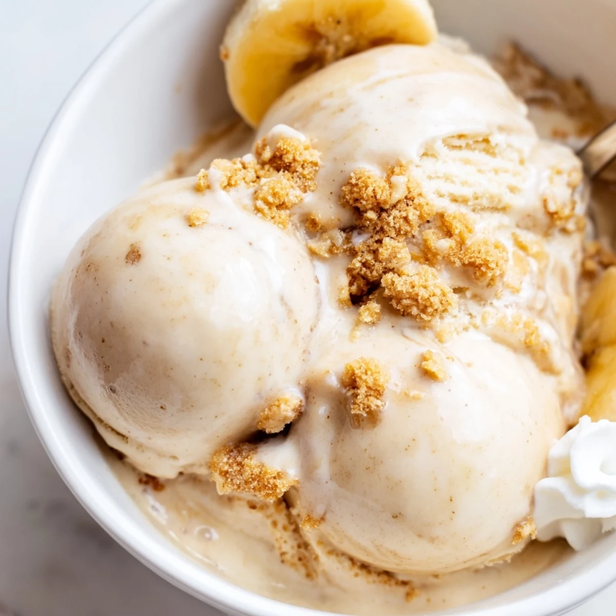 Ninja Creami Banana Cream Pie Ice Cream topped with whipped cream and sliced banana