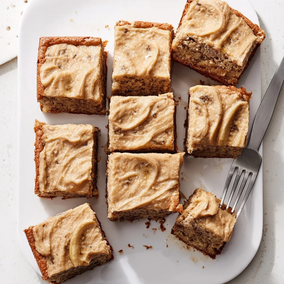 Golden banana bread brownies topped with velvety brown butter frosting swirls