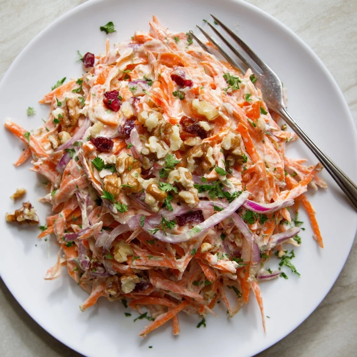 Tangy apple carrot slaw recipe featuring shredded carrots and sweet apples in white bowl