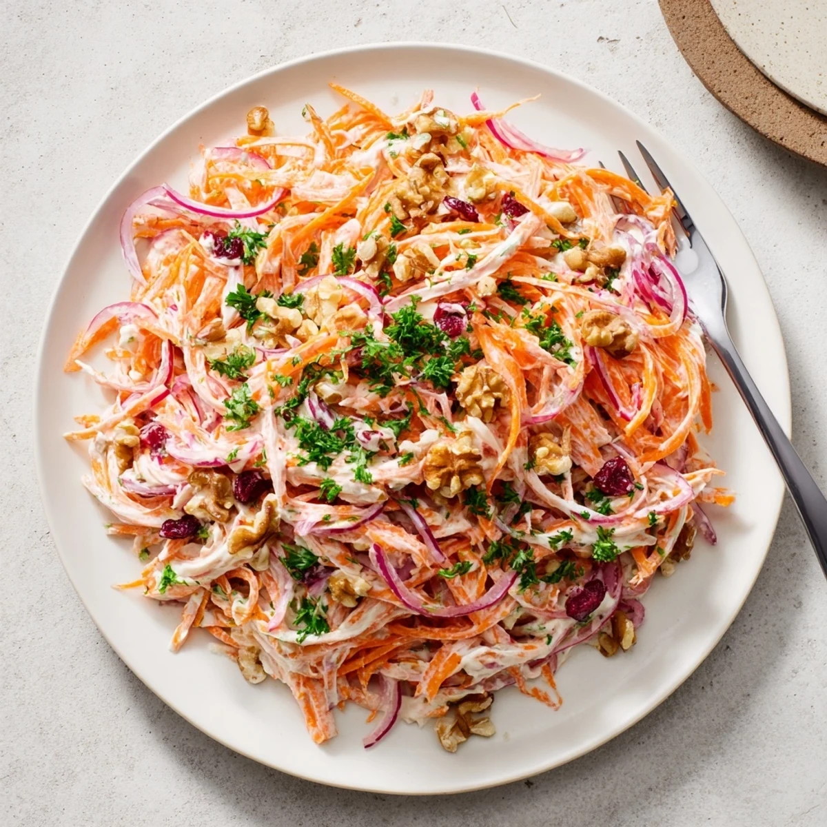 Colorful bowl of apple carrot slaw topped with parsley and optional toasted walnuts