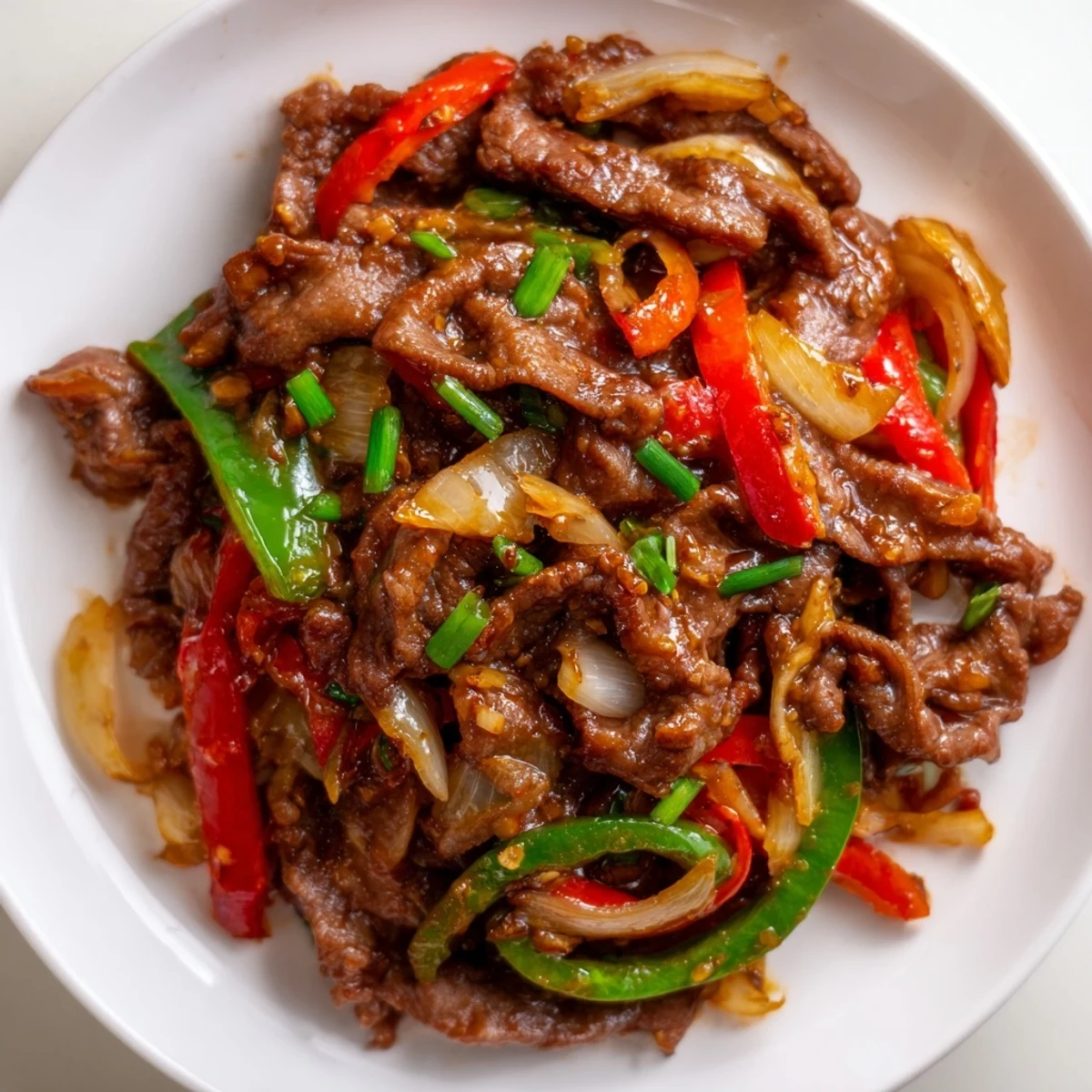 Tender strips of beef and colorful bell peppers coated in glossy spicy chili garlic stir fry sauce