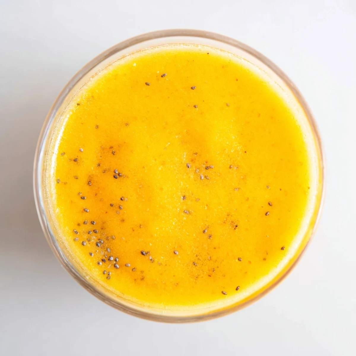 Glass of refreshing tropical pineapple mango smoothie with fresh mango slice on rim