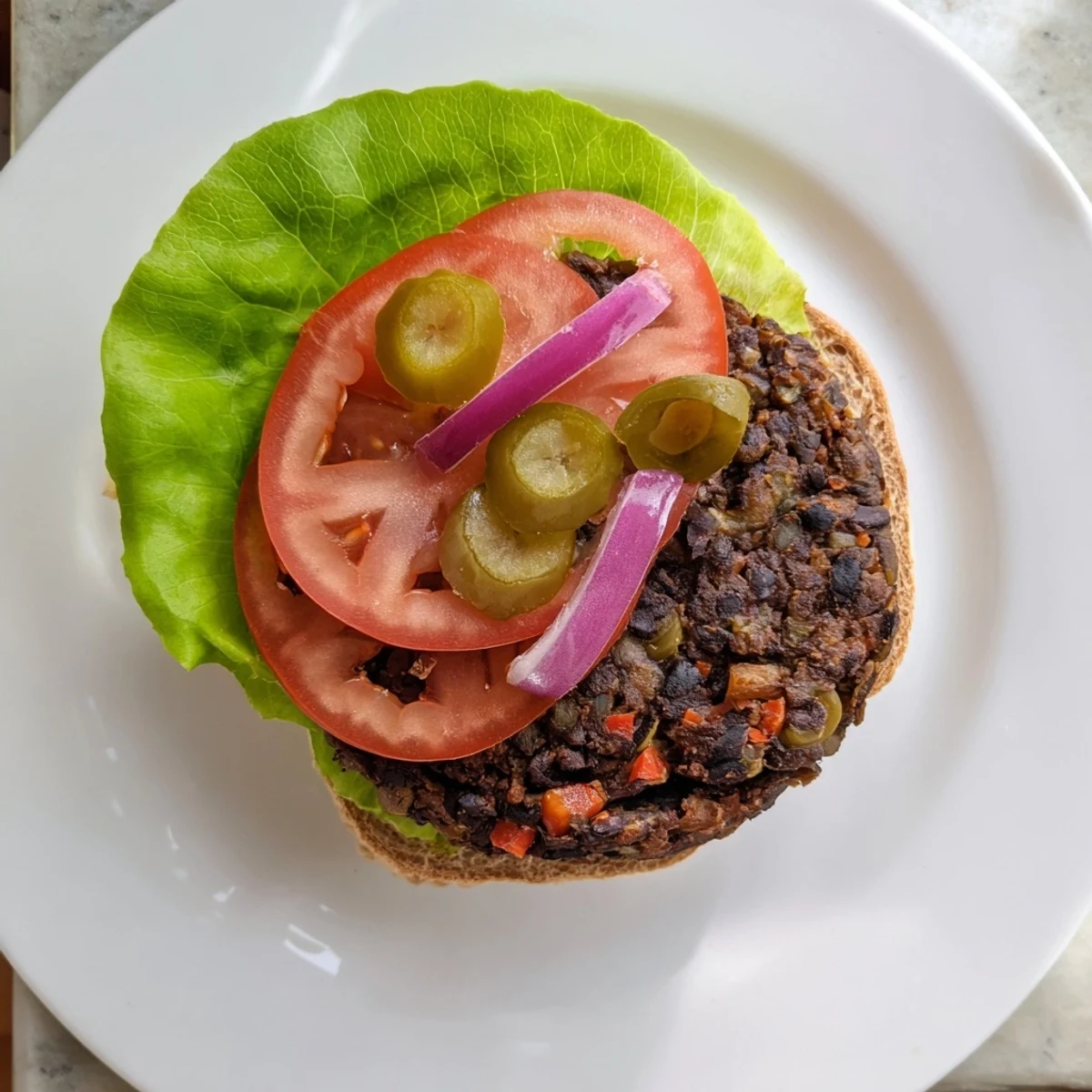 Hearty black bean veggie burger patties sizzling in a cast iron skillet with fresh vegetables