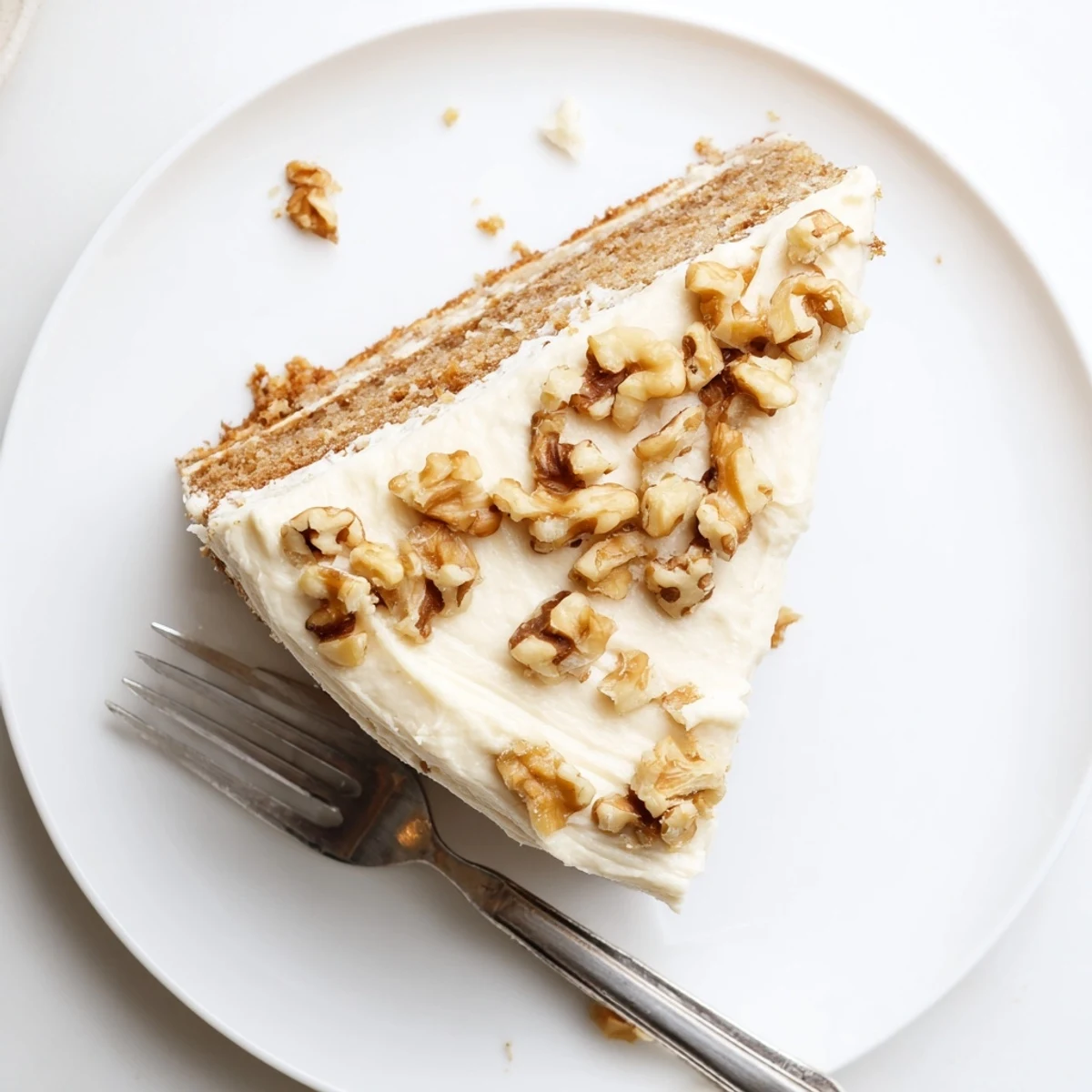 Close up of moist banana cake slice with cream cheese frosting and walnuts
