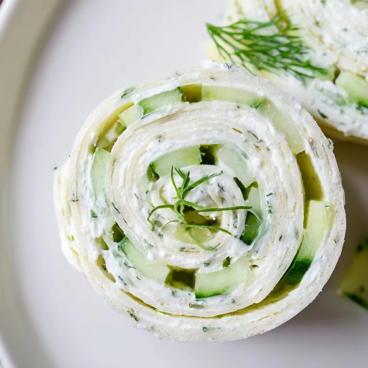 Cucumber And Dill Pinwheels arranged on platter, creamy centers and fresh dill.