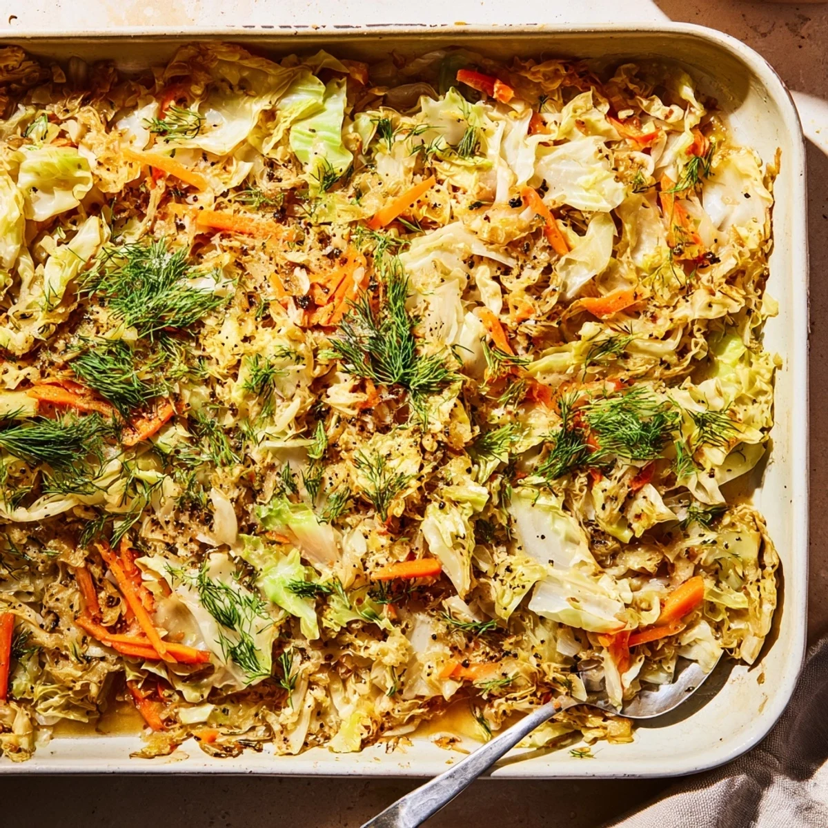 Golden brown slow roasted cabbage and sauerkraut casserole topped with melted gruyère cheese and fresh dill