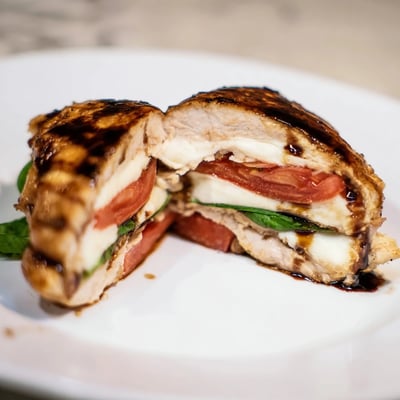 Sliced Caprese Stuffed Chicken Breast showing melted mozzarella, tomato, and fresh basil filling.