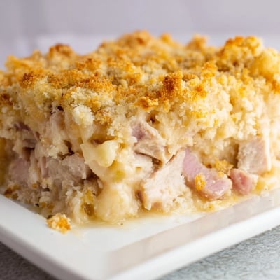 Slice of creamy Chicken Cordon Bleu Casserole served on a white plate with salad.