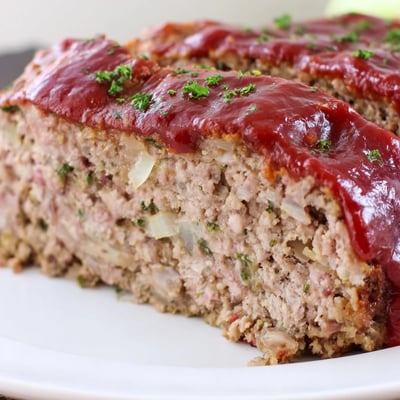 Golden-brown turkey meatloaf topped with sticky brown sugar glaze, resting on a rustic wooden cutting board for a homey feel.