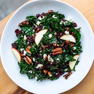 Freshly tossed Winter Kale Salad with Dried Cranberries, topped with crumbled feta cheese and set against a rustic wooden background for a cozy winter meal.