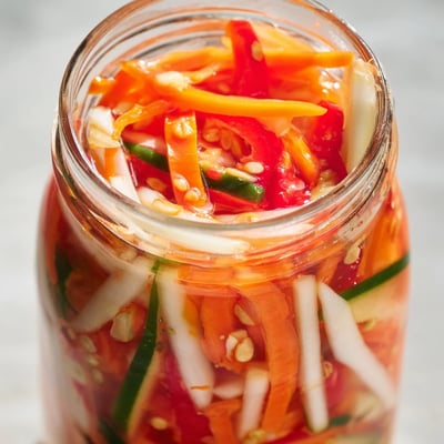 Bowl of Vietnamese Vegetable Pickle Medley garnished with garlic and peppercorns, served as banh mi filling.