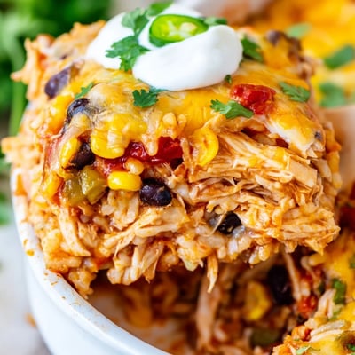 Creamy chicken burrito casserole with black beans, corn, and rice in a rustic baking dish
